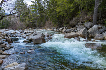 Pure mountain water of the stormy stream of the Pemi Gewasser River (The Pemi) in early spring among large stones. Lincoln Woods Trail in the White Mountains, NH