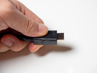 a black hdmi cable is clutched in the man's hand. cable to connect the home media
