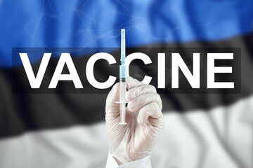 A syringe with a vaccine in the doctor's hand against the background of the Estonian flag. COVID-19 corona virus, immune protection, treatment against nCoV infection 2019, vaccination.