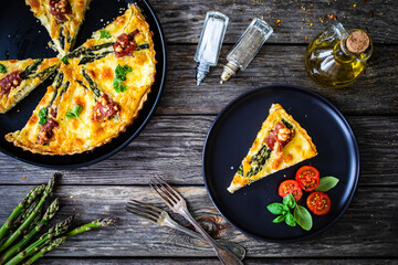 Tart with asparagus and serrano ham on wooden table

