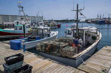 Lobster Boat Docking:  A small fishing boat loaded with lobster traps ties up at a commercial...