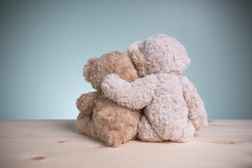 Concept family, love, and valentines festival. Brown teddy bears sitting huggy show love, happiness on an old wooden table with copy space.