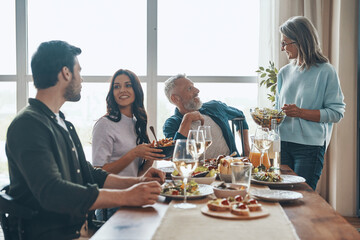 Modern multi-generation family enjoying dinner and smiling while sitting in the modern apartment