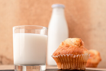 Isolated glass of milk, along with a cupcake and a bottle of milk in the background.