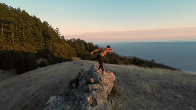 Aerial of a ballet dancer dancing on a rock at sunset. San Francisco, USA