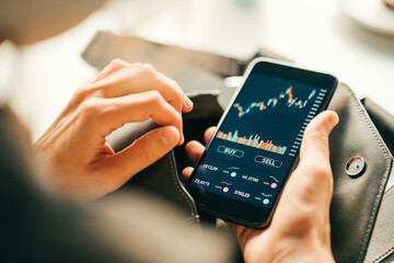 Woman using smartphone investing application. Stock market investment app in hand. Screen close-up