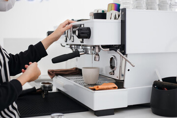 Barista wearing white face mask using coffee machine to make coffee