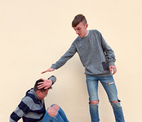 A young male bully threatening to hit a crouched scared male
