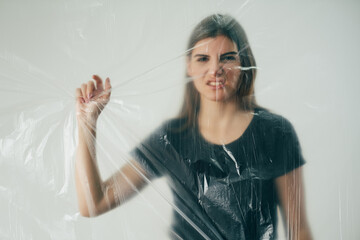 Female protest. Feminist movement. Human rights. Defocused angry woman activist hand grasping behind clear wrinkled plastic film isolated on white out of focus background.