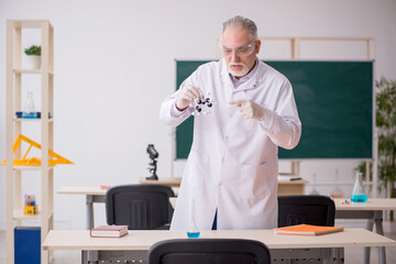 Old male chemist teacher in the classroom