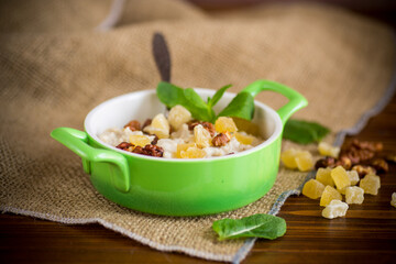 cooked boiled sweet oatmeal with nuts and candied fruits in a bowl