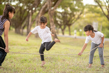 Happy kids playing together with jumping rope outdoors