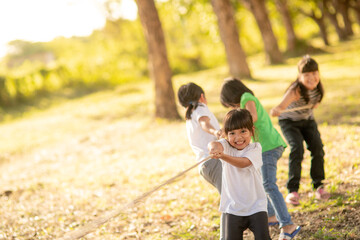 Children playing tug of war at the park on sunsut