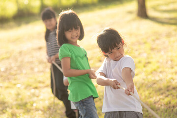 Children playing tug of war at the park on sunsut