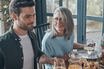 Happy senior mother and son smiling while having dinner together