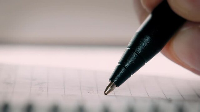 Extremely close-up of a pen writing. A person makes notes in a notebook with a ballpoint pen. Close-up macro.