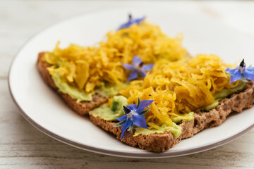 Home made avocado toasts with curried sauerkraut, garnished with boretch flowers.