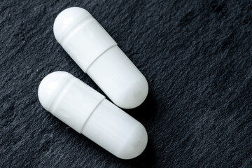 macro photo of tablets in a capsule shell pill on a black background