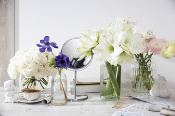 white roses, pink ranunculus, blue anemones, yellowish buttercups, lilies in round vases on the table for a special occasion as a kitchen decoration. Copy space