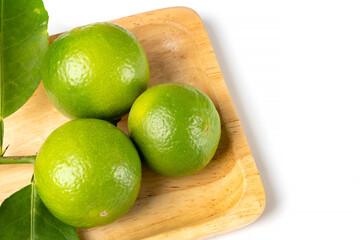 Close up natural fresh lime, green leaf, on wooden dish, white background.