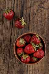 rustic red strawberry at bowl on a wooden table top. above view