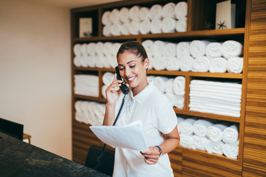 Beautiful young woman working at hotel in spa department and talking on phone.
