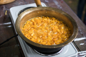 Cooking pumpkin jam with lemon and spices in a copper basin on a gas stove