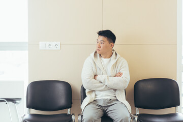 young asian man waiting for an interview or meeting sitting in the hallway in the waiting room....