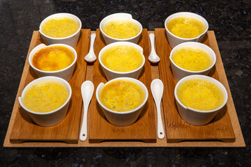 Traditional Cream brulee , creme brulée, with natural vanilla beans in ramekins with spoons and lined up in depth of field blur