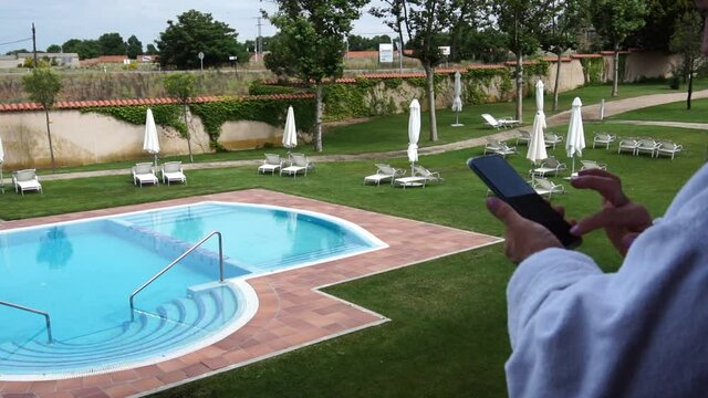 Looking at the cell phone on vacation by a pool