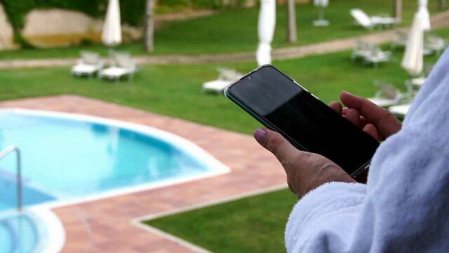 Looking at the cell phone on vacation by a pool