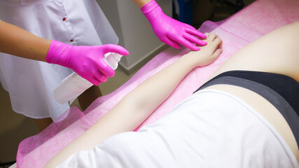 preparatory work for the procedure of sugar hair removal, the master sprays a special spray on the model's hand