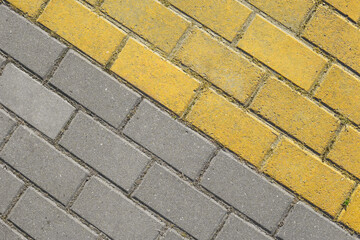 Diagonal grey and yellow paving slabs top view. Bricks as street road, paving stone texture. Abstract paving stone background.