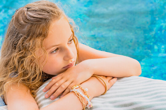 Beautiful young girl relaxing on a chair near swimming pool. Young model lying on sun lounger. Hight quality photo