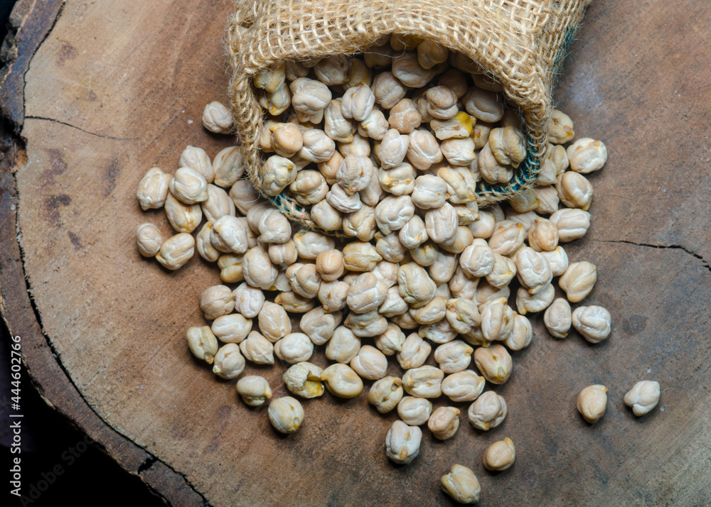 Wall mural Chickpeas in wooden plank on dark background.