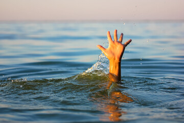 A man is drowning in water. A hand peeks out from under a water. A drowning person needs help,...