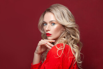 Stylish mature blonde model woman with red lips makeup and healthy curly hair on red banner background, portrait