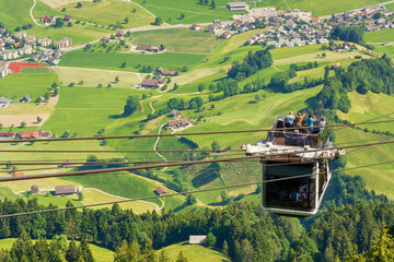 Tourists (faces not visible) climbing the cable car in an open car up Mount Stanserhorn in...