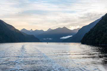 Sun rising over Doubtful Sound, Clouds hanging low on the mountains, Fiordland National Park, New Zealand