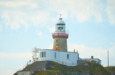 Fototapeta na wymiar A look on famous landmark lighthouse and Dublin bay on a cloudy sunny day from Howth Head Summit.