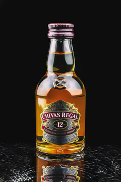 bottle of chivas regal whiskey with reflection on broken glass on dark background