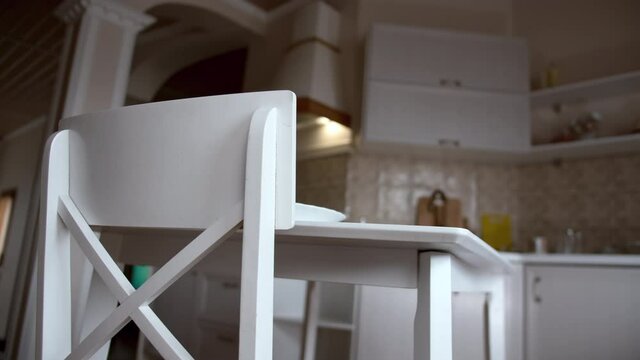 woman moves the chair to the table in the kitchen, everything is ready for dinner, cinematic shot