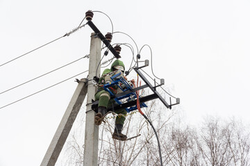 Repair of electrical networks. Power electrician lineman at work on pole. Electrician are climbing on electric poles to install and repair power lines.