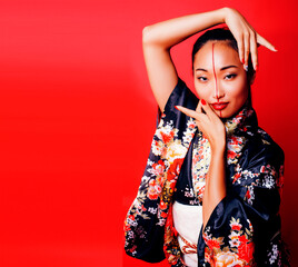 young pretty geisha on red background posing in kimono, oriental