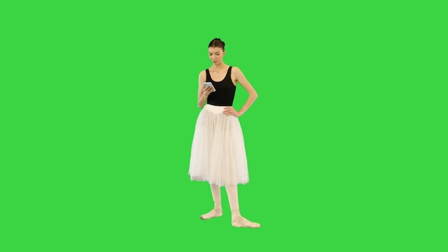 Tired ballerina with her smartphone on the break of training on a Green Screen, Chroma Key.