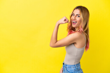 Young woman over isolated yellow background doing strong gesture