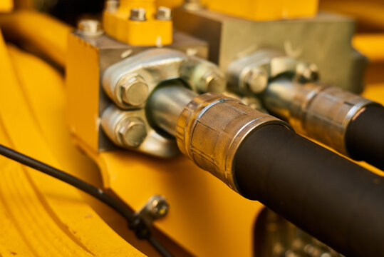 Close up view of hydraulic pipes of heavy industry machine. Low key.