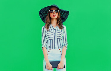 Portrait of beautiful young woman wearing a black round summer hat, white striped shirt on a blue background