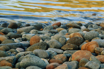 sea surface and stones on the beach. Sea, reflection of sea waves and cliffs in aegean sea