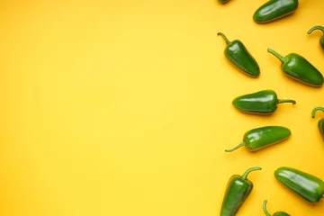 Fotobehang Chili Pepers Green chili pepper. Group of jalapeno peppers on a yellow background, place for text, top view.  © VI Studio